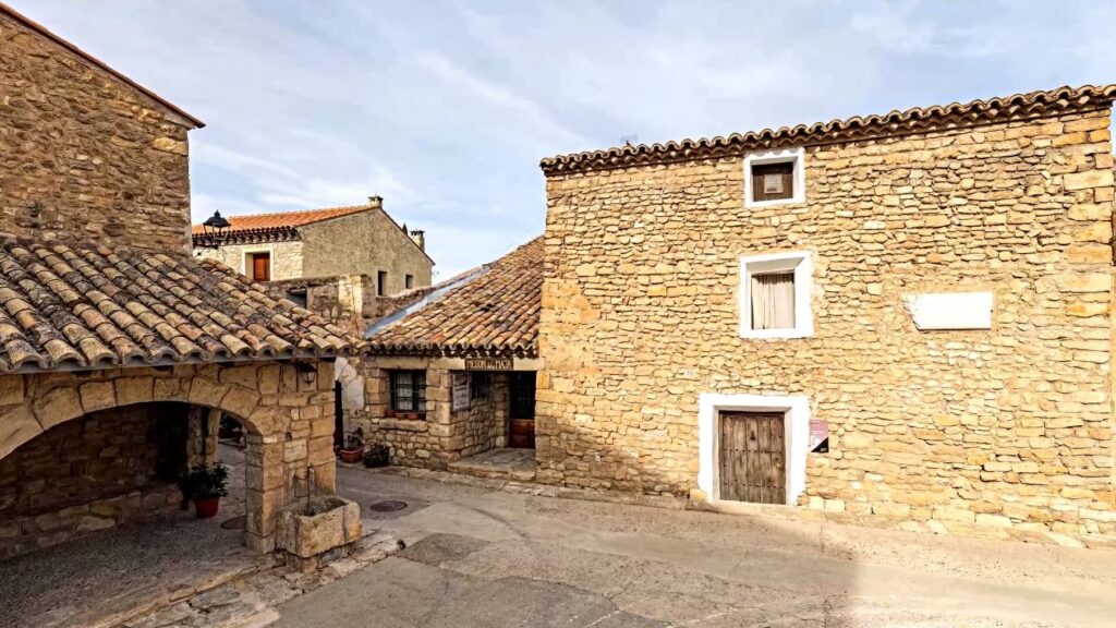 Casas tradicionales de piedra con tejados de arcilla se alzan en una plaza rústica de Fuendetodos.