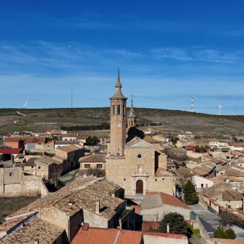 Una iglesia de piedra con una torre esbelta domina una panorámica del pueblo rural de Fuendetodos.