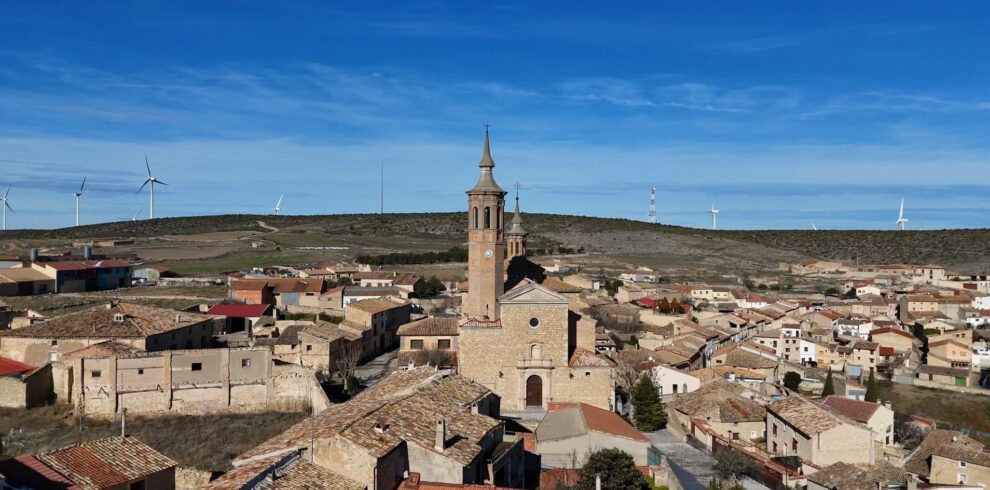 Una iglesia de piedra con una torre esbelta domina una panorámica del pueblo rural de Fuendetodos.