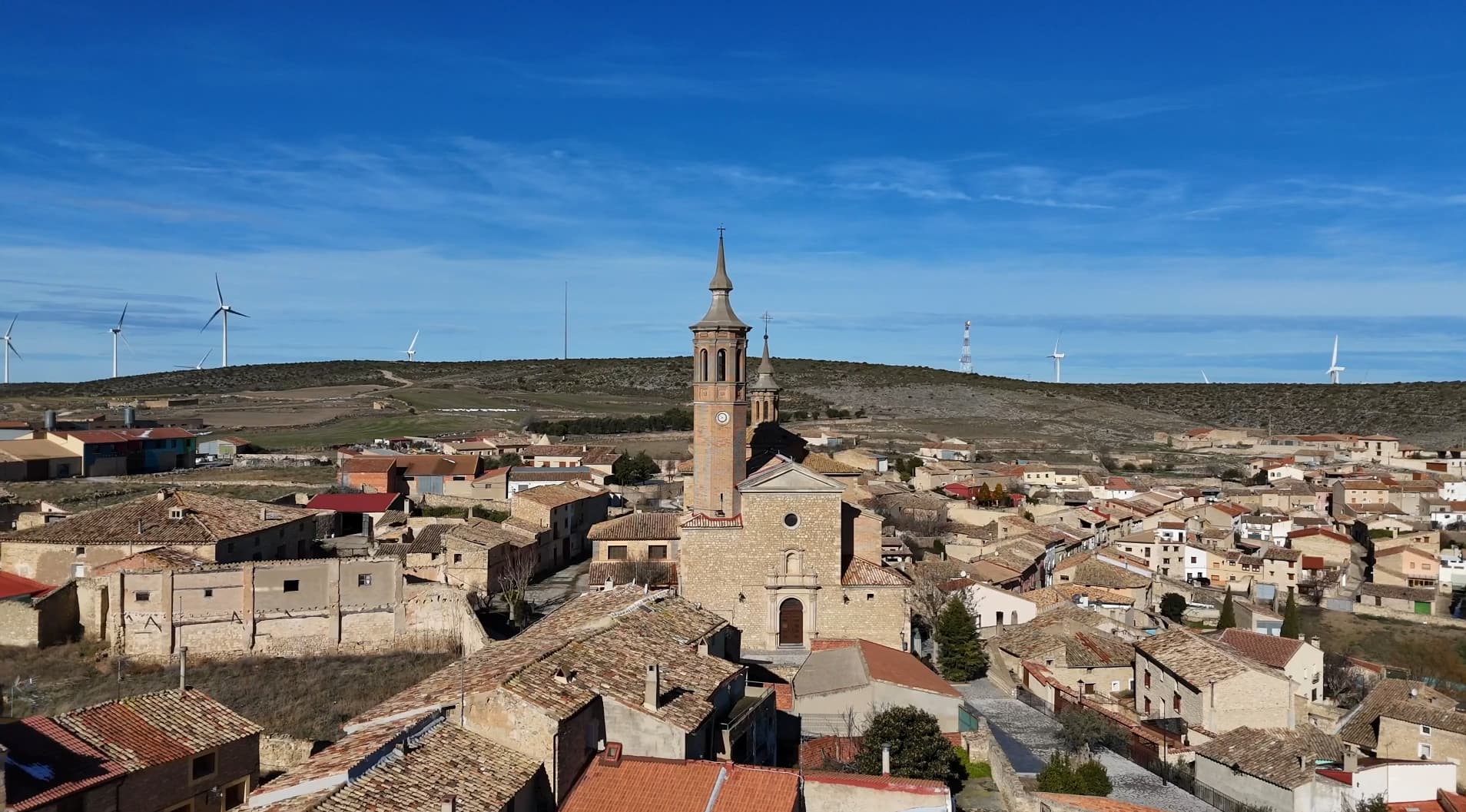 Una iglesia de piedra con una torre esbelta domina una panorámica del pueblo rural de Fuendetodos.